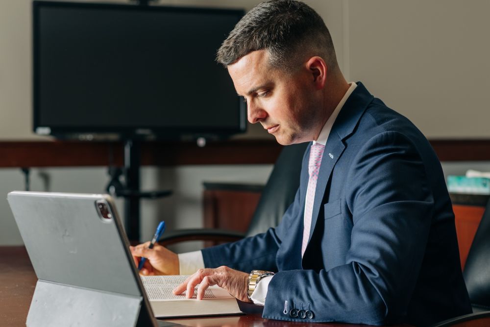 David Willingham David Willingham in suit writing at desk with laptop.