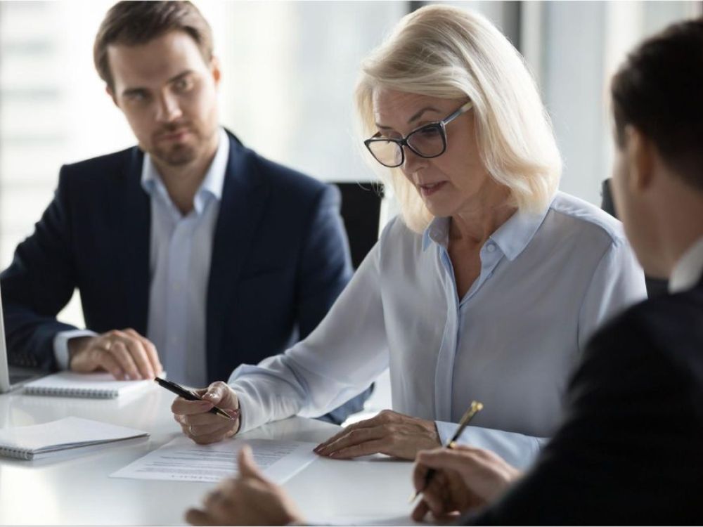 Business meeting with focused professionals discussing documents at a conference table.