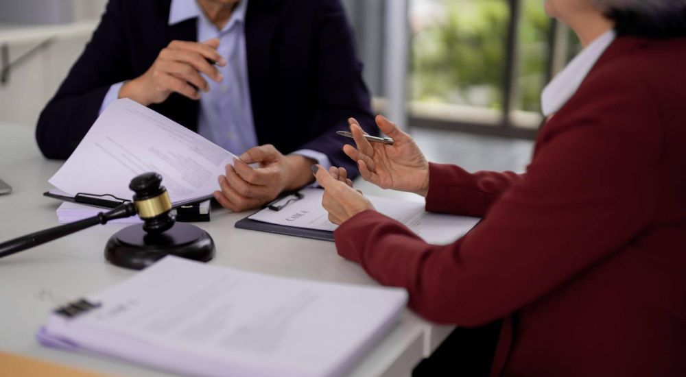 Two professionals reviewing legal documents at a desk with a gavel and paperwork.
