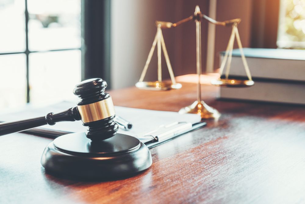 Gavel and scales of justice on a wooden desk, symbolizing law and legal decisions in a courtroom setting.
