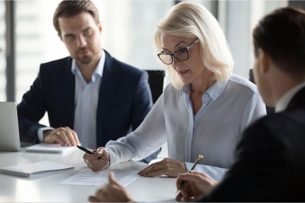 Business meeting with focused professionals discussing documents at a conference table.